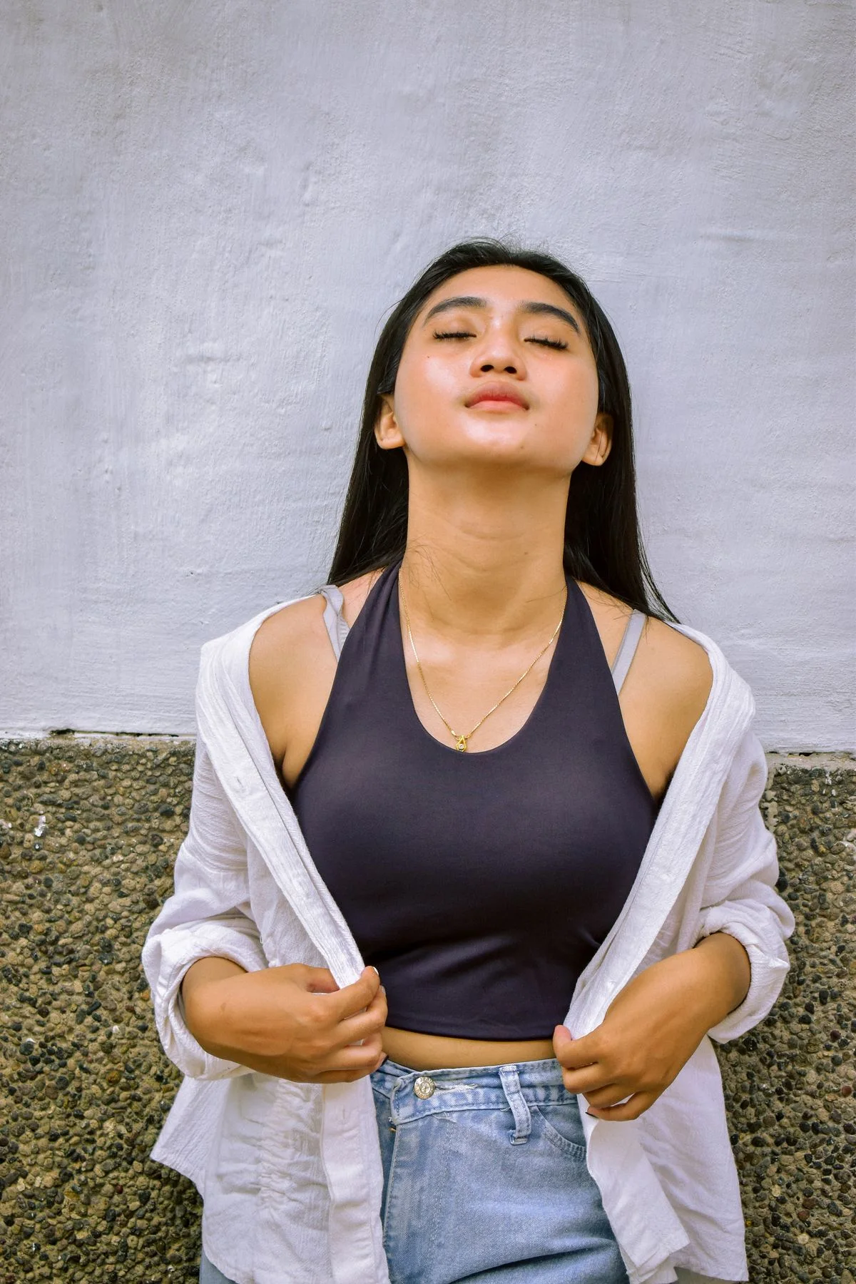 灰色墙面前闭眼站立的女士原始照片